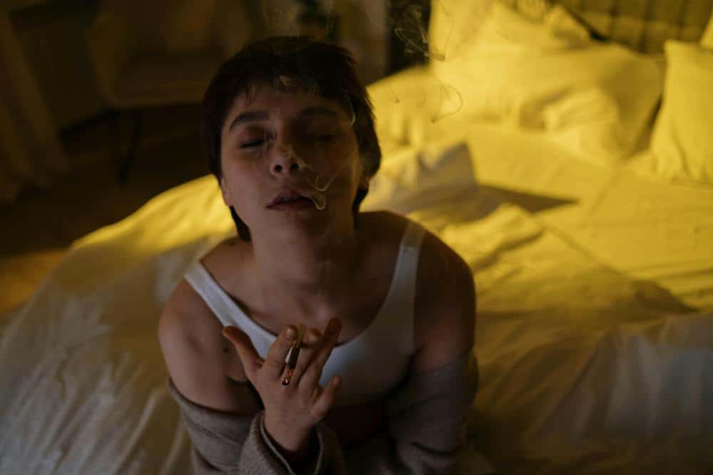 woman sitting on bed smoking joint